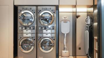 A modern laundry facility with two stacked washing machines and a drying machine.