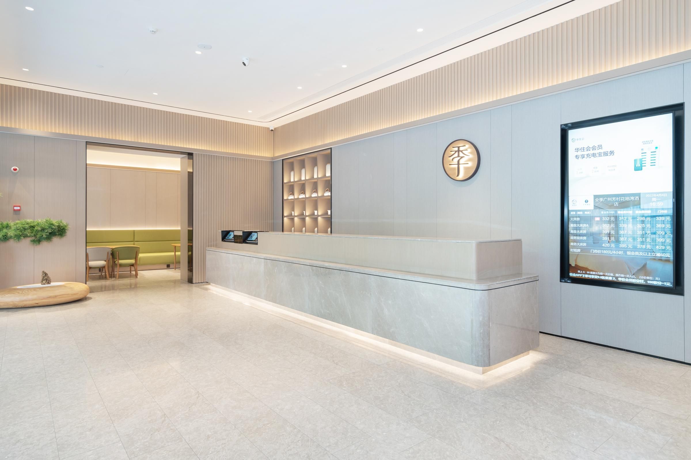 A modern reception area with a marble counter, a digital display, and a seating area with chairs and a sofa.