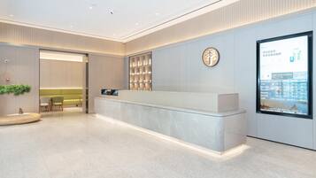 A modern reception area with a marble counter, a digital display, and a seating area with chairs and a sofa.