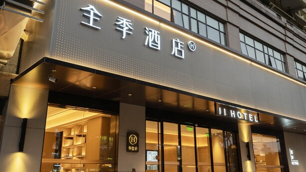 Ji Hotels facade med oplyst skilt og et moderne udtryk.