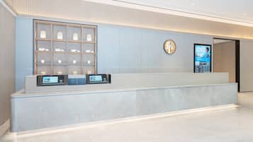 Un mostrador de recepción moderno con una pantalla digital, una exhibición de objetos decorativos y un logo en la pared.