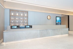 A modern reception desk with a digital screen, a display of decorative items, and a logo on the wall. - Ji Hotel Guangzhou Fangcun Huadiwan (Guangzhou)