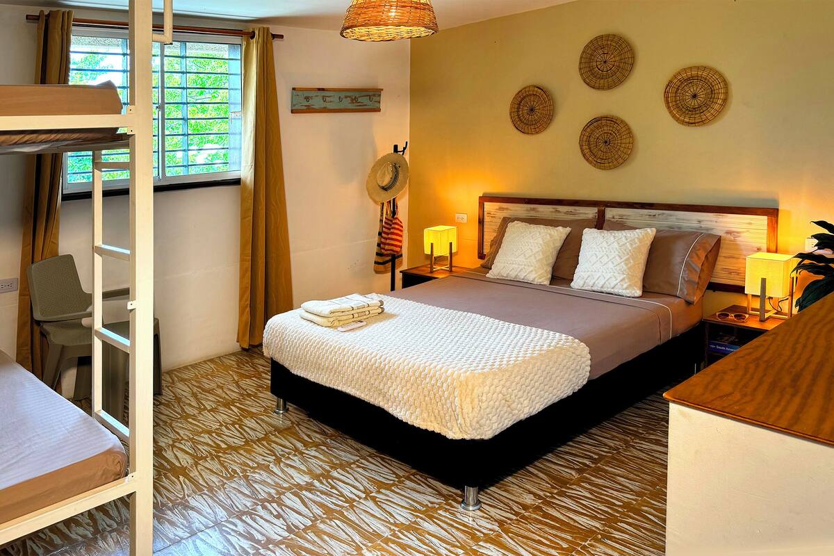 A bedroom with a bunk bed, a desk, a chair, a bedside table with lamps, and decorative wall art.