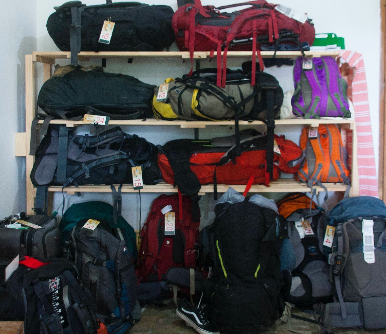 A storage area with shelves holding various backpacks and suitcases.