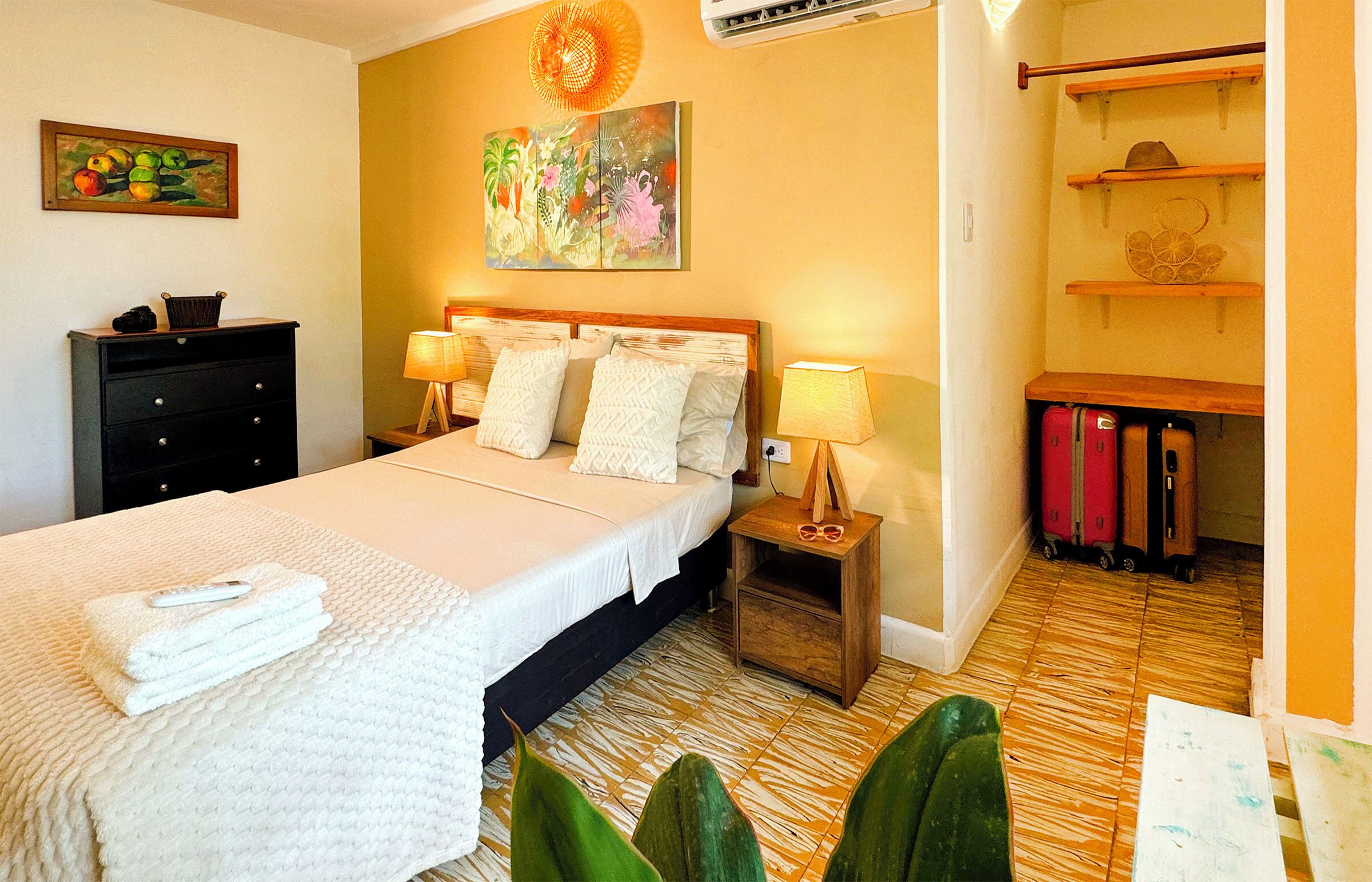 Habitación de hotel con cama, mesitas de noche, cómoda y una pared decorada con obras de arte.