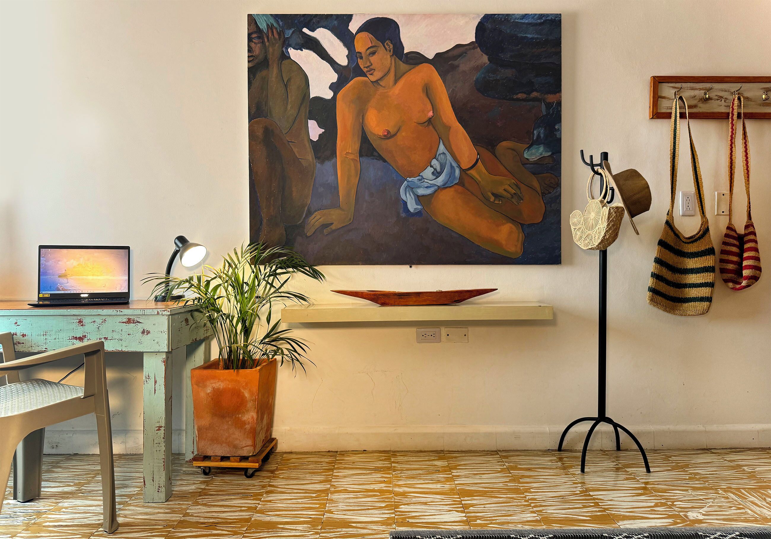 A room with a painting, a desk with a computer, a chair, a potted plant, a shelf with bags, and a tiled floor.