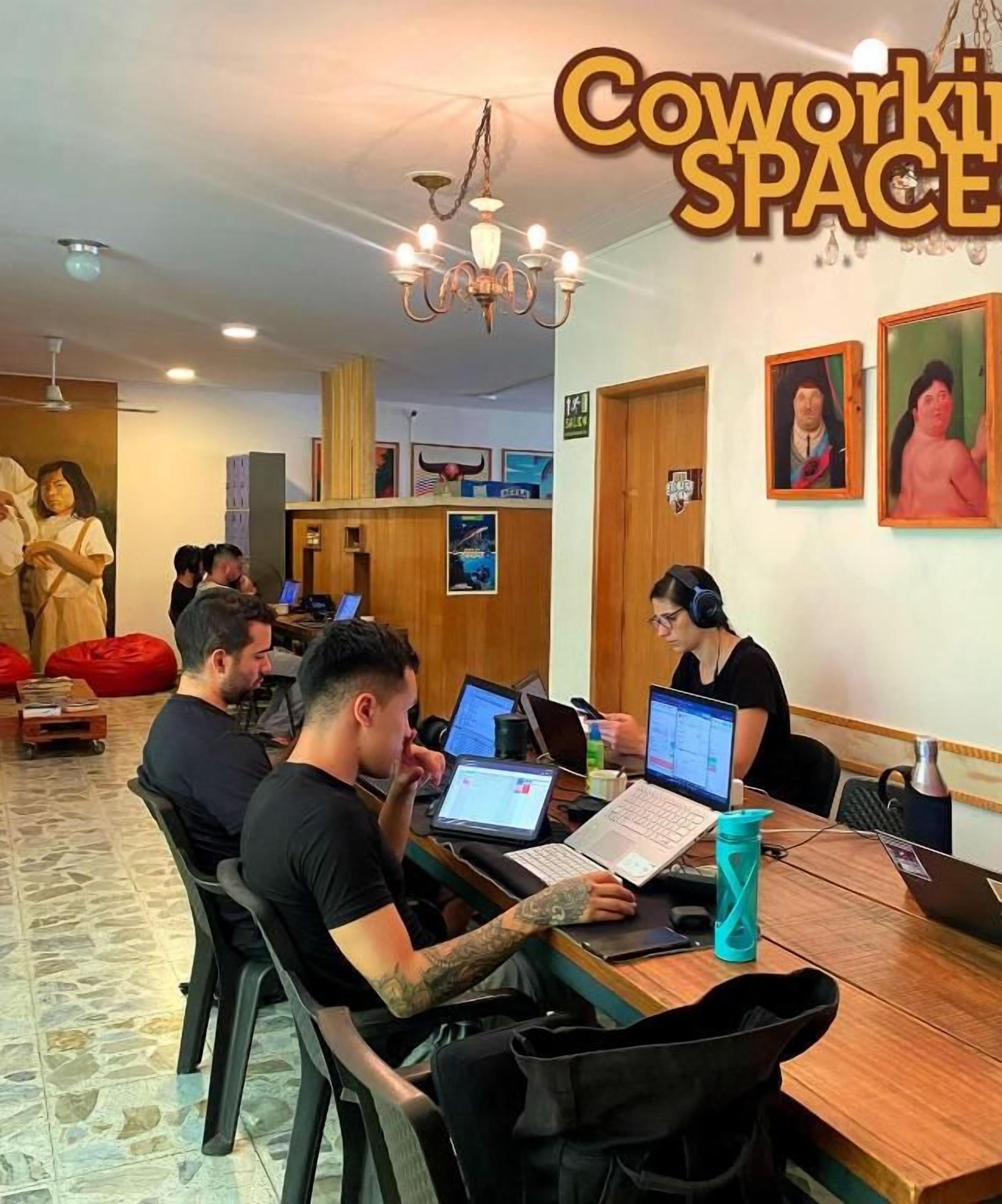 A coworking space with a wooden table, chairs, and people working on laptops.