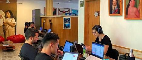 A coworking space with a wooden table, chairs, and people working on laptops.