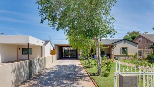 Un quartier résidentiel avec un chemin menant à une entrée fermée par un portail, entouré de maisons et de verdure.