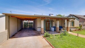 Une maison de plain-pied avec un patio couvert, une pelouse devant et un garage.