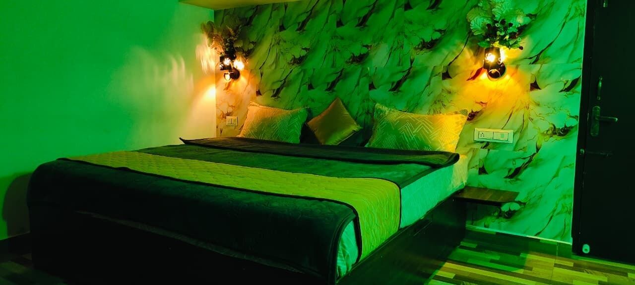 A bedroom with a bed, green walls, and two wall-mounted light fixtures.