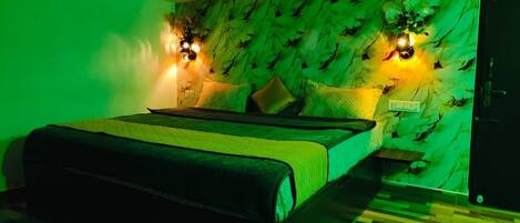 A bedroom with a bed, green walls, and two wall-mounted light fixtures.