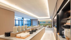 A modern hotel lobby with a long reception counter, seating area, and large windows. - Ji Hotel Guangzhou Xintang South Station (Guangzhou)