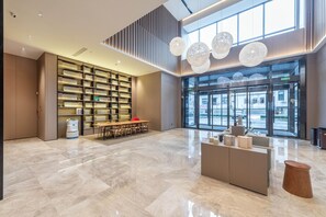 A spacious lobby with a high ceiling, a large seating area, a reception desk, and a large window offering a view of the street. - Ji Hotel Guangzhou Xintang South Station (Guangzhou)