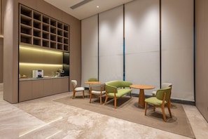 A modern interior with a kitchen area, seating arrangement, and a large wall with vertical lines. - Ji Hotel Guangzhou Xintang South Station (Guangzhou)
