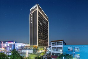 A high-rise hotel with multiple floors, a prominent sign at the top, and a parking lot in the foreground. - Ji Hotel Guangzhou Xintang South Station (Guangzhou)