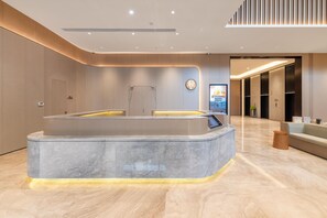 A modern reception area with a marble reception desk, a seating area, and a clean, minimalist design. - Ji Hotel Guangzhou Xintang South Station (Guangzhou)