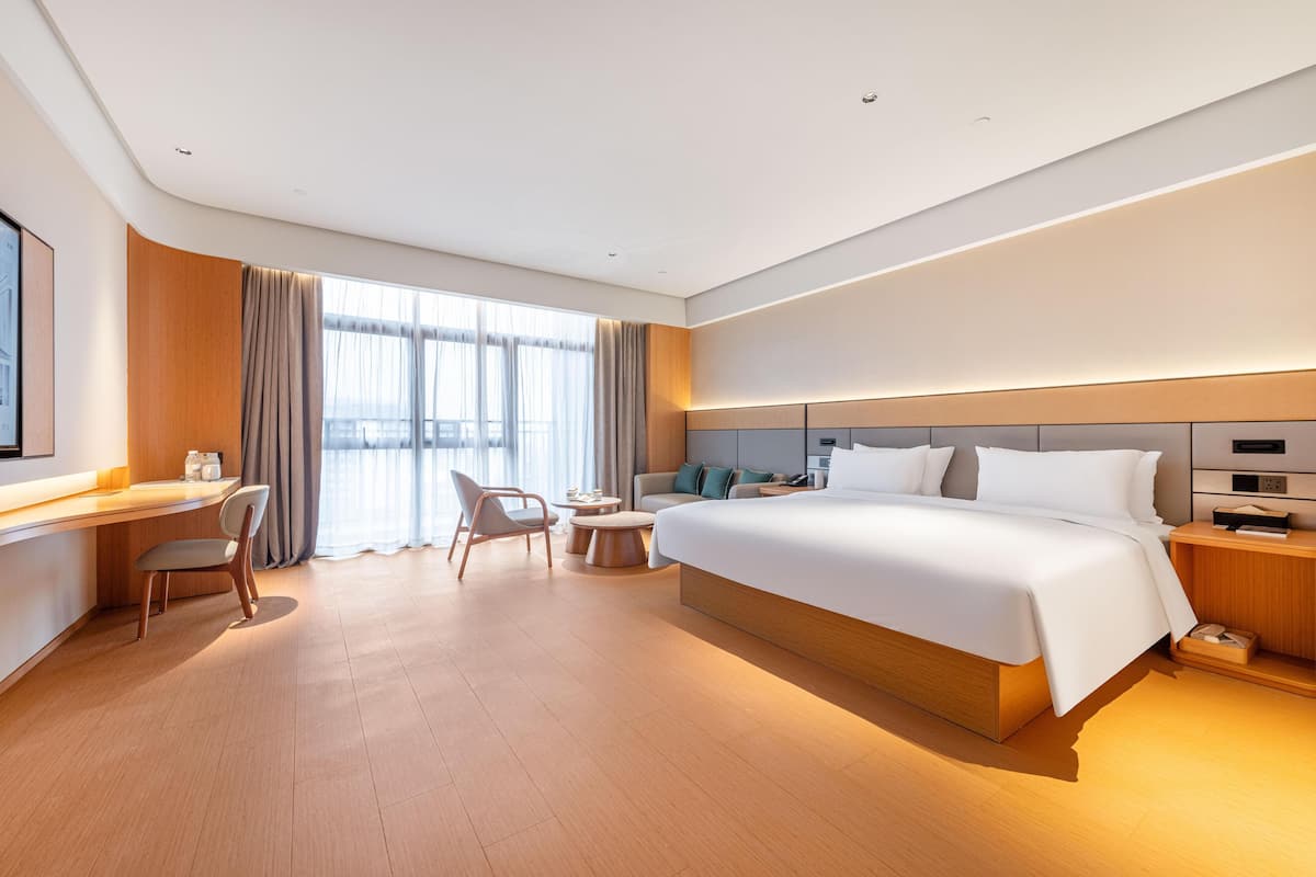 A modern hotel room with a large bed, a desk, and a chair.