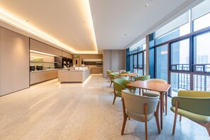 Un hall d’hôtel moderne doté d’un îlot central, d’un espace salon et de grandes fenêtres offrant une vue panoramique.