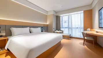 A modern hotel room with a large bed, a desk, and a chair.