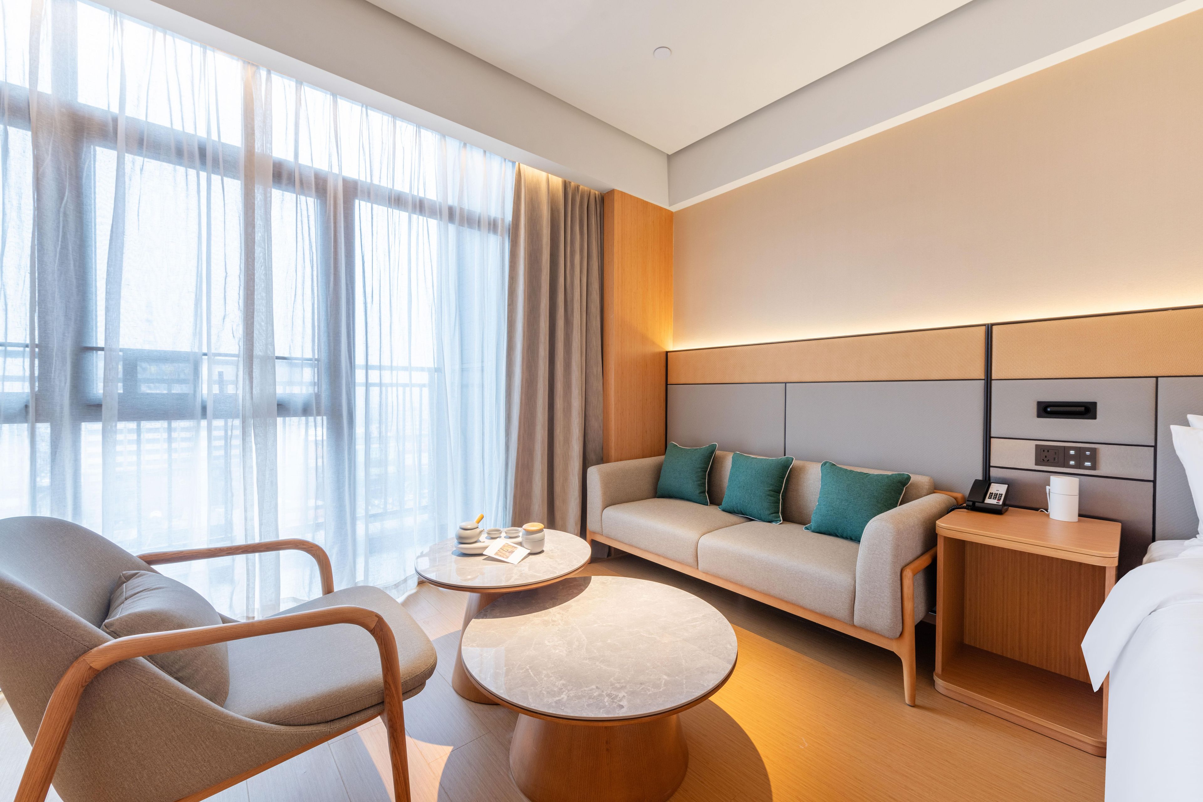 Een moderne hotelkamer met een bank, fauteuil en een rond bijzettafeltje.