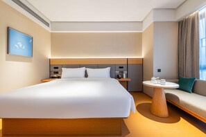 A modern hotel room with a large bed, a bedside table, a round coffee table, and a sofa. - Ji Hotel Guangzhou Xintang South Station (Guangzhou)
