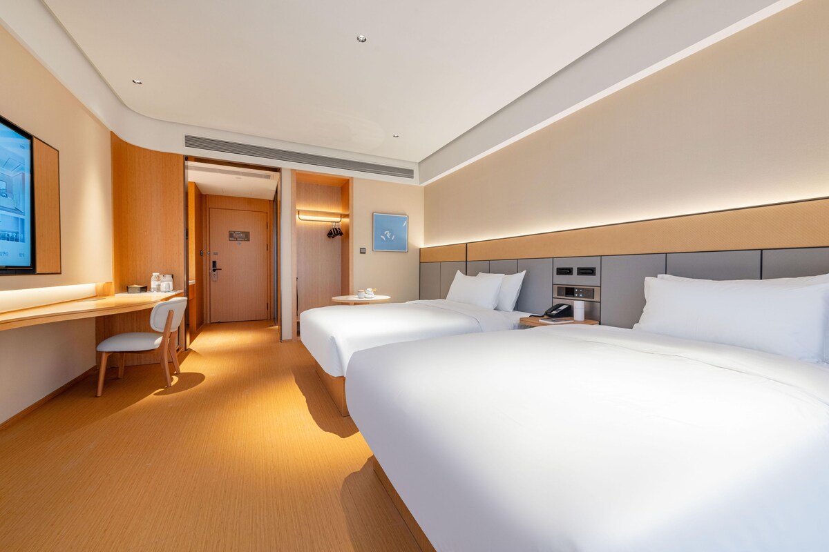 Une chambre d’hôtel avec deux lits, un bureau, une chaise et une petite table.