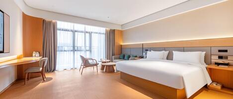 A modern hotel room with a large bed, a desk, and a chair.