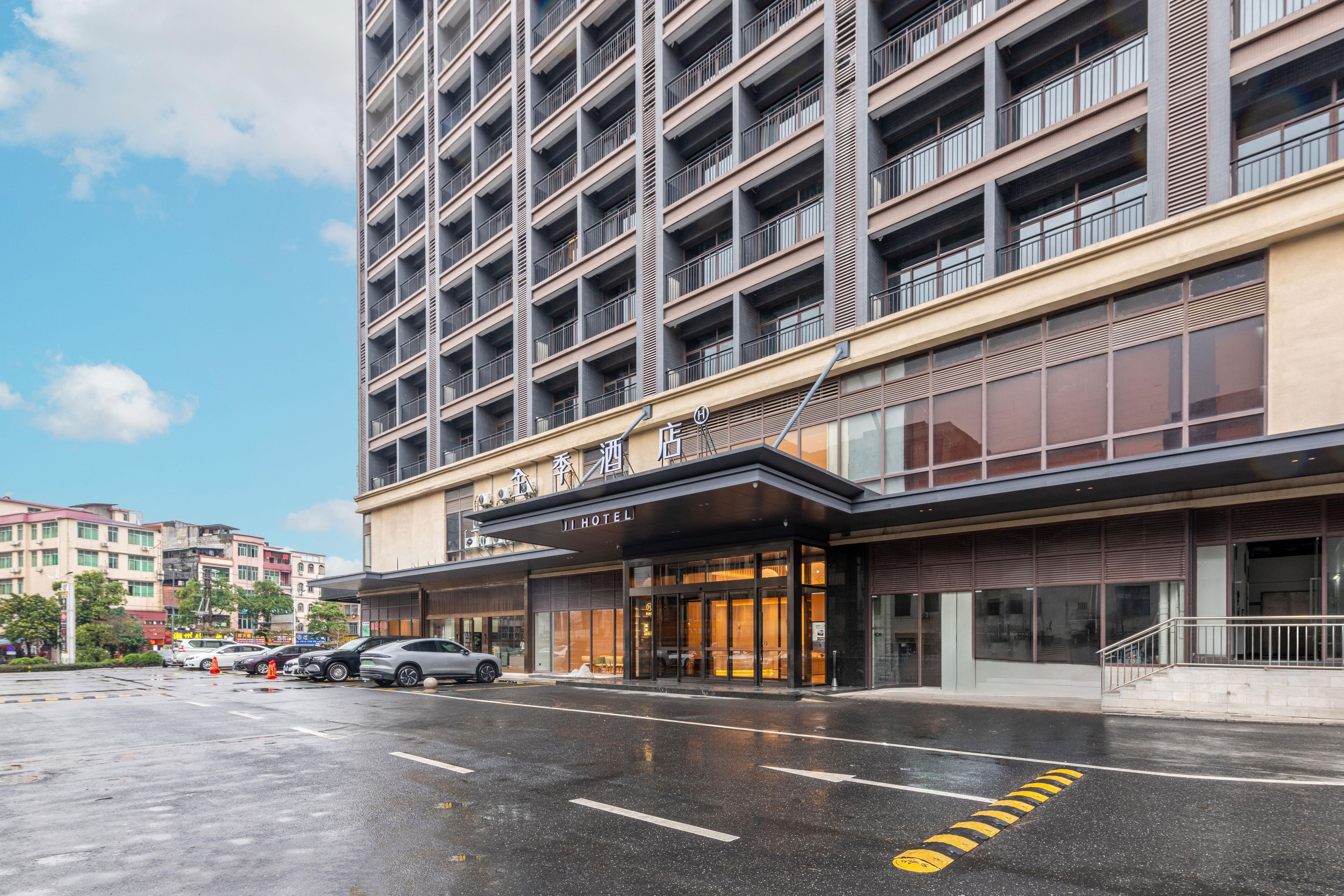 A hotel with a modern facade, multiple balconies, and a parking lot.