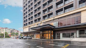 A hotel with a modern facade, multiple balconies, and a parking lot.