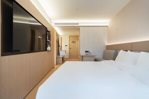 A modern hotel room with a large bed, a flat-screen TV, a small desk, and a seating area. - Ji Hotel Guangzhou Xintang South Station (Guangzhou)