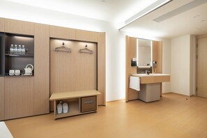 A modern hotel room with a wooden vanity, a bench with shoe storage, and a mirror above the sink. - Ji Hotel Guangzhou Xintang South Station (Guangzhou)
