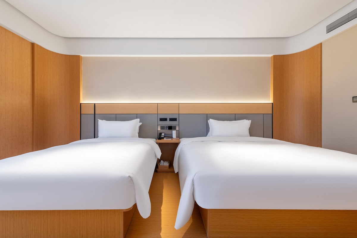 A hotel room with two beds, a bedside table, and a modern design.