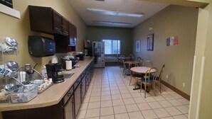 A kitchen with a coffee machine, refrigerator, and dining table with chairs.