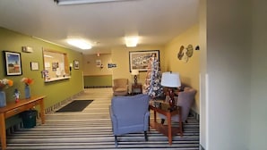A hotel lobby with a striped carpet, a reception desk, a blue armchair, and a Christmas tree.