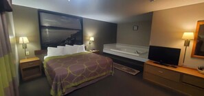 Una camera d'albergo con un letto, una televisione, una vasca da bagno e due comodini con lampade.