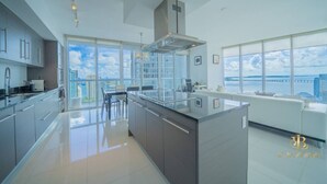 Eine moderne Küche mit einer großen Kochinsel, einem Essbereich und großen Fenstern mit Blick auf die Stadt.