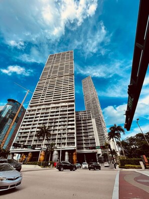 Un edificio moderno de gran altura con fachada de entramado, varios pisos y una entrada destacada con marquesina.