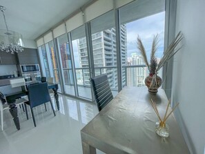 A modern kitchen with a dining area, large windows, and a view of high-rise buildings. - Lavish Condo w/ Breathtaking Views (Miami)