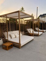 Outdoor seating areas with wooden frames and white cushions, set on a concrete surface.