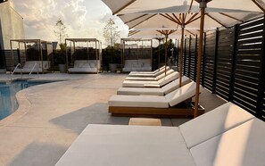 A poolside area with sun loungers, a small seating area, and a pool. - The Amaya (Fort Wayne)