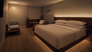 Een moderne slaapkamer met een groot bed, een nachtkastje, een stoel, een klein tafeltje en een hanglamp.
