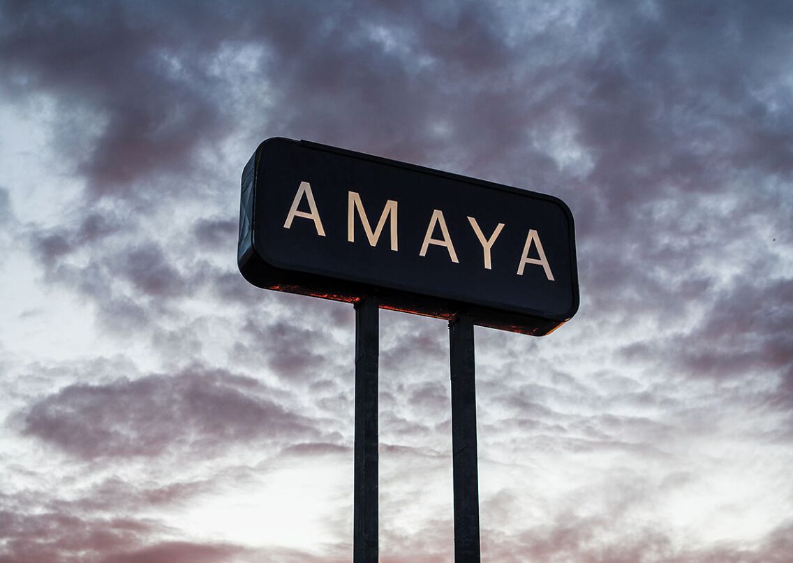 A sign with the word "AMAYA" against a cloudy sky.