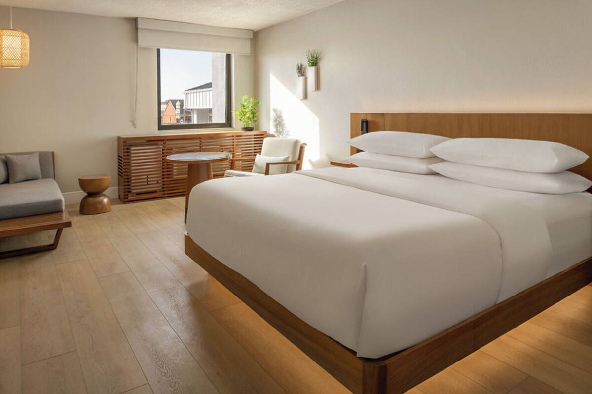 A modern bedroom with a large bed, a wooden headboard, a small round table, and a sofa.