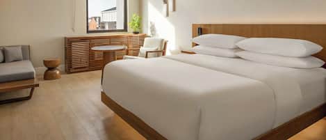 A modern bedroom with a large bed, a wooden headboard, a small round table, and a sofa.