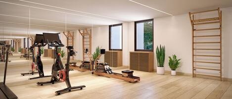 Ein geräumiger Fitnessraum mit Trainingsgeräten, Holzböden, großen Fenstern und Topfpflanzen.