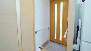 A narrow hallway with a wooden door, a white wall, and a white floor. - Shinjuku Deep Lane White House・ZHUOJU (Tokyo)