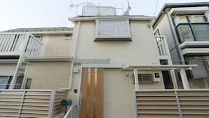 A modern two-story building with a beige facade, a wooden gate, and a small window. - Shinjuku Deep Lane White House・ZHUOJU (Tokyo)