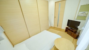 A bedroom with a bed, a TV, a small wooden table, and a wardrobe. - Shinjuku Deep Lane White House・ZHUOJU (Tokyo)