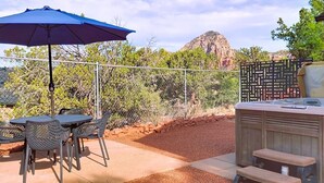 Eine Terrasse im Freien mit Tisch, Stühlen, einem blauen Sonnenschirm und einem Grill.